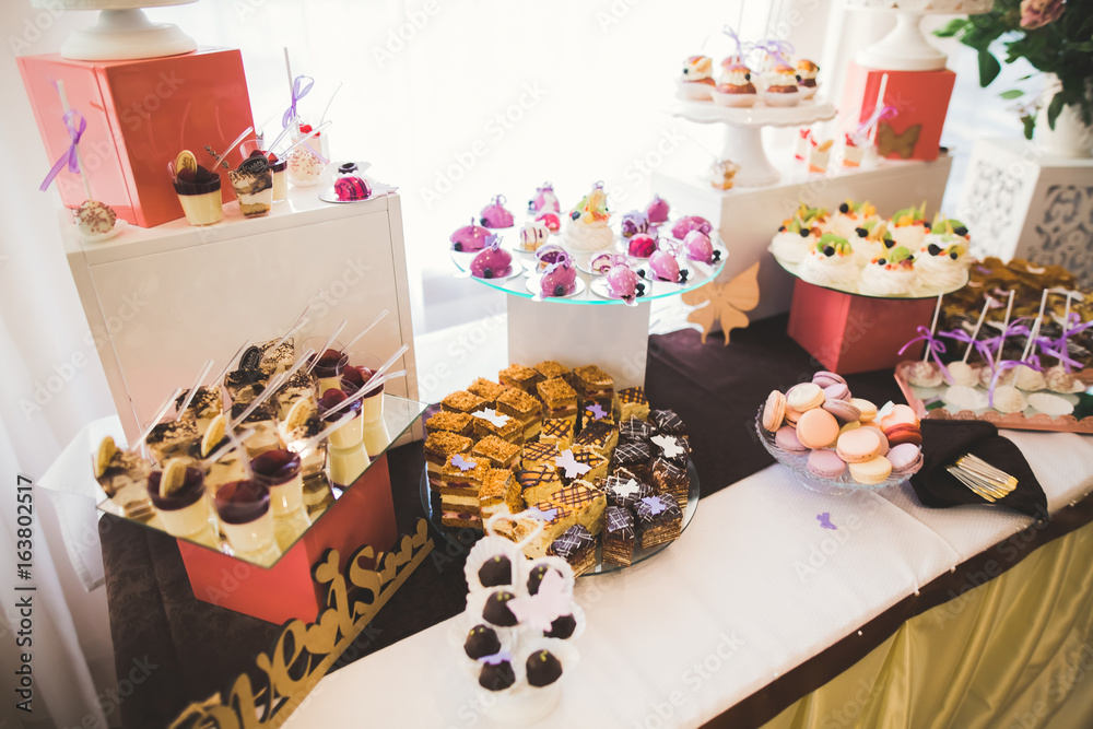 Delicious and tasty dessert table with cupcakes shots at reception closeup