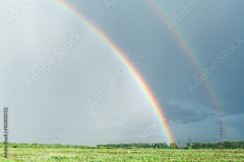 Rainbow over the green field. Landscape background