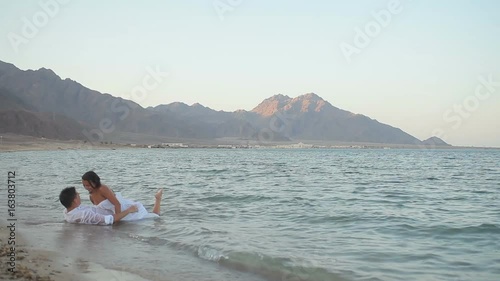 Young couple hugging and kissing lying in the sea