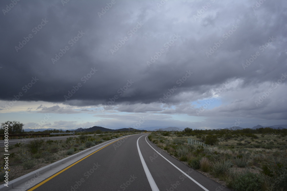 Naklejka premium Dark storm clouds over rural countryside with mountains and open land