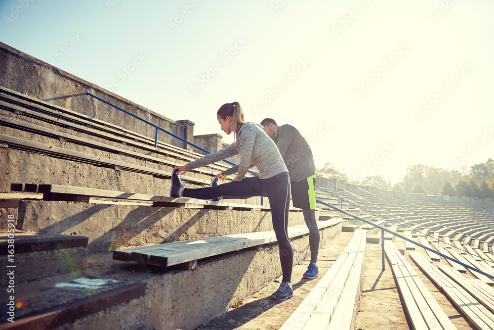 couple stretching leg on stands of stadium couple stretching leg on stands of stadium