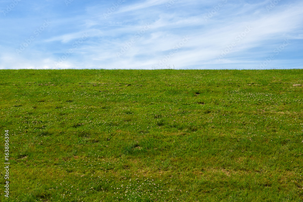 Dike with green Meadow and blue sky