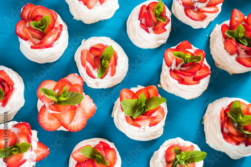 Homemade small strawberry pavlova meringue cakes pattern with cream top view