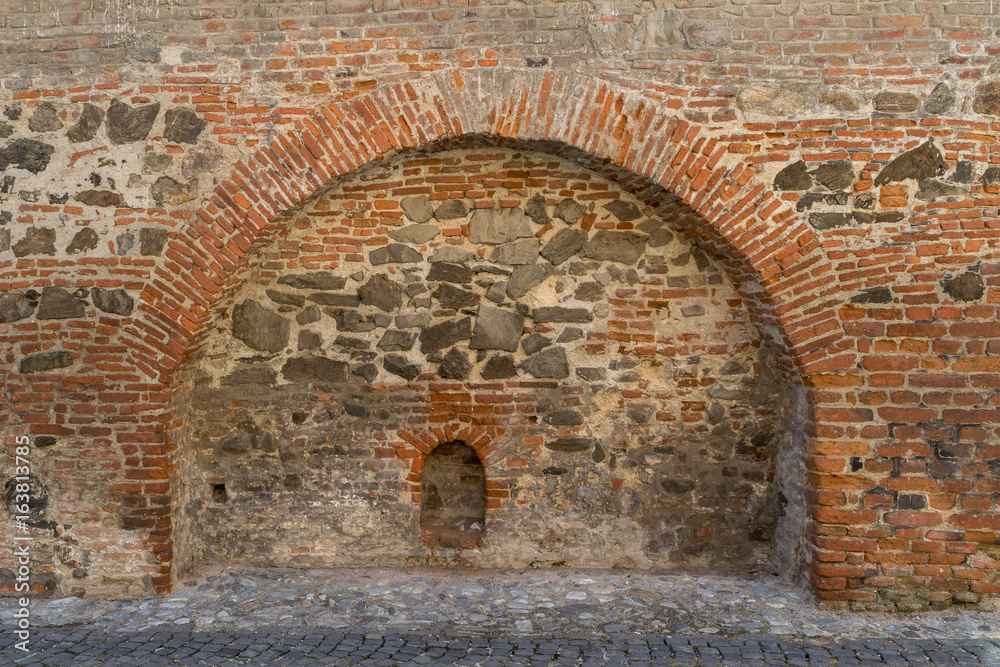 Brick and stone medieval wall with an arch