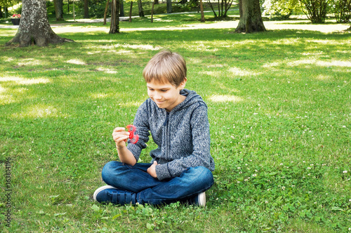 Child sitting on the grass and playing with spinner