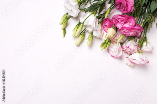 Pink and white eustoma flowers on white textured background. Floral mock up.View from above.