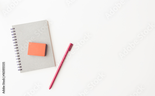 notebook paper, red sticky note, paper clip and pen on white background flat lay