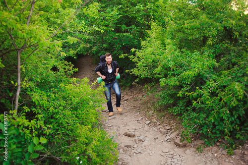 Traveler man walking with backpack in rocky mountains. Travel concept.