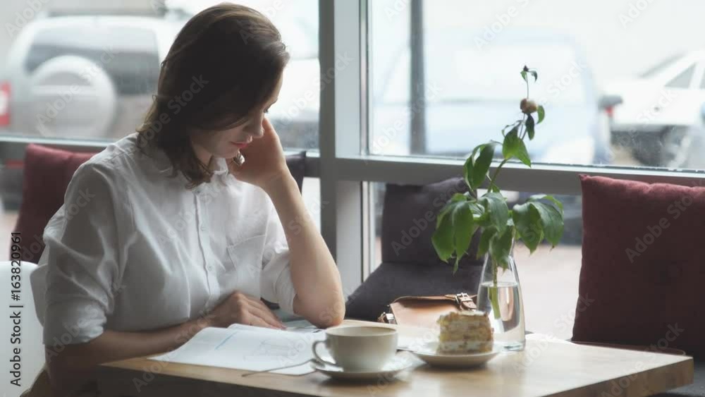 young business woman is resting during a lunch break at a cafe and leafing through women's fashion magazine young business woman is resting during a lunch break at a cafe and leafing through women's fashion magazine