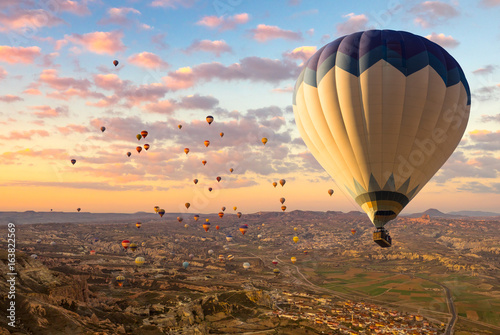 Cappadocia landscape at sunrise - hot air balloons flying over mountain valley in Goreme, wide panorama.