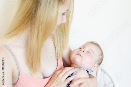 Young happy mother with sleeping infant boy