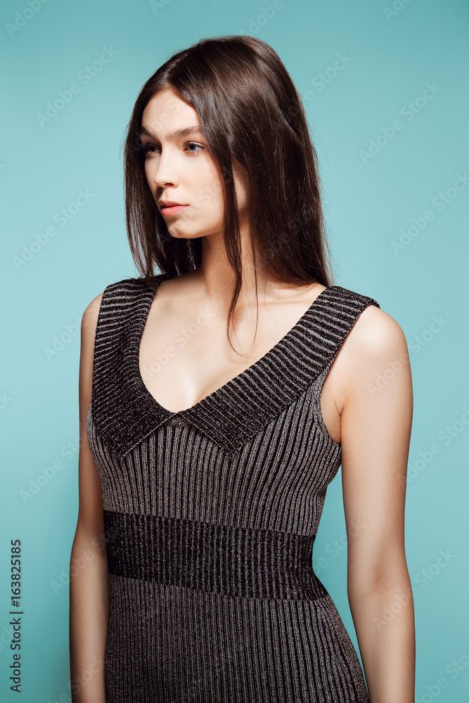 Obraz premium Pretty girl posing in sleeveless dress with deep decollete.