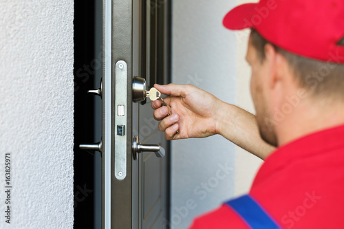 door lock service - locksmith working in red uniform photo