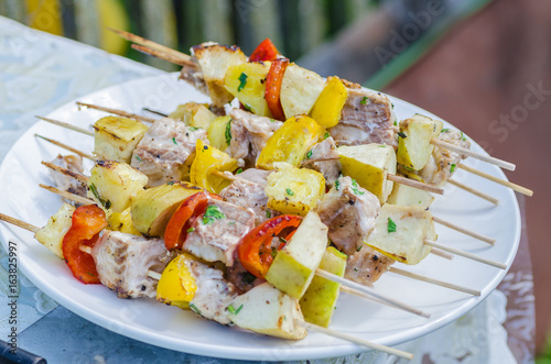 Tasty skewers of fresh fish with vegetables and apples on a wooden shish kebab