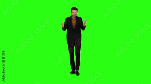 Young guy is happy with his victories, he is happy. Green screen. Slow motion photo