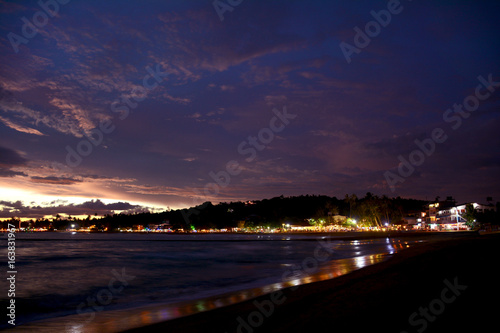 Beautiful night view of the illuminated Unawatuna tropical beach on the background of colorful twilight sky, Sri Lanka