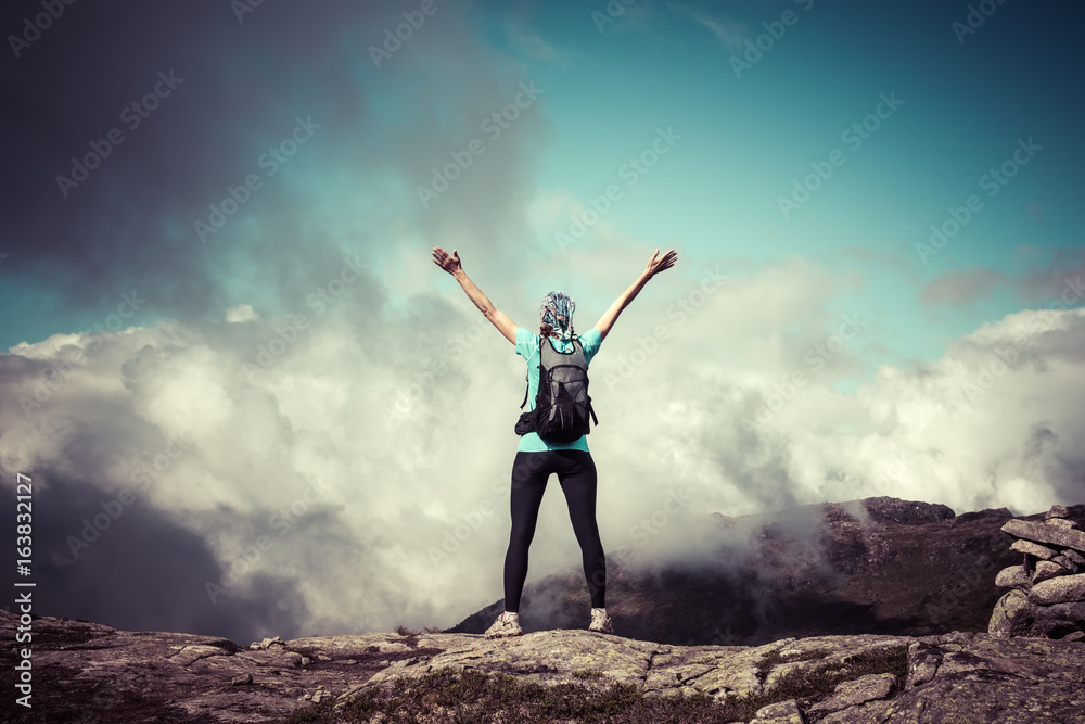 Young woman with backpack standing on fjord coast Young woman with backpack standing on fjord coast