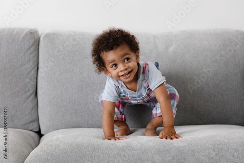 smiling toddler crouching on couch