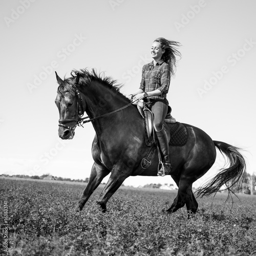 Young happy girl enjoying riding horse on green field at sunny day © skumer