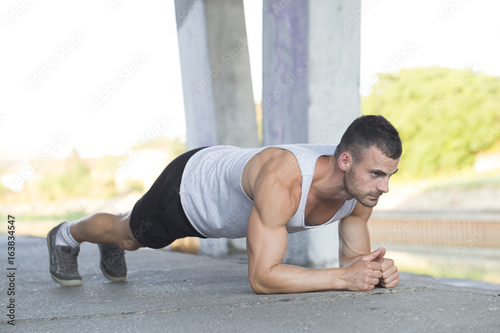 Young muscular young man doing push ups outdoors Young muscular young man doing push ups outdoors