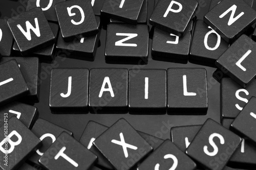 Εκτύπωση καμβά Black letter tiles spelling the word jail on a reflective background