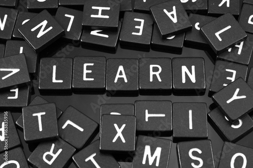 Black letter tiles spelling the word "learn" on a reflective background
