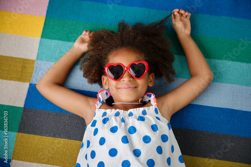 smiling girl with afro hair and heart-shaped sunglasses