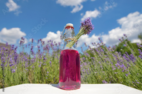 Homemade lavender syrup in a glass bottle in front of lavender