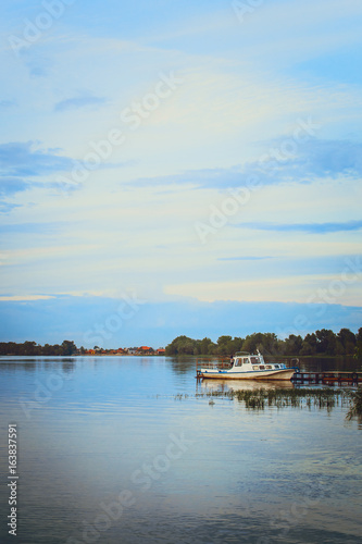 White boat on the river near the shore. Summer landscape. Russia. Vertical photography.