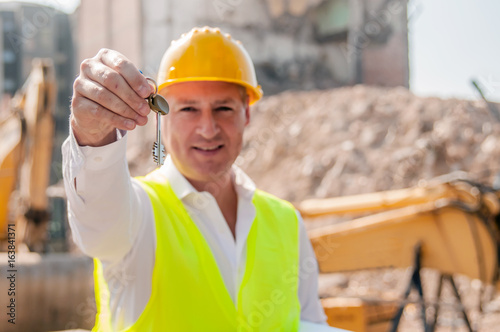 Engineer on building site showing key from new home