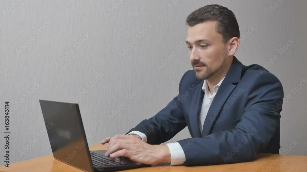 Businessman working on laptop and calming down. A man gets scary information online. A person works on a computer and can not solve problems Businessman working on laptop and calming down. A man gets scary information online. A person works on a computer and can not solve problems