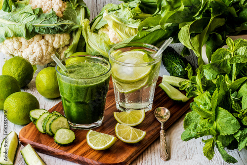 green smoothie and detox water with lime, mint and ice on wooden background. detox diet.