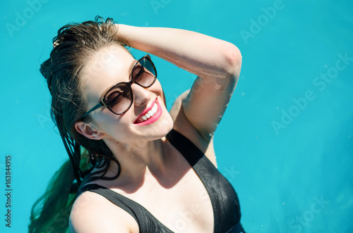 Portrait of young sexy lady swimming in the pool