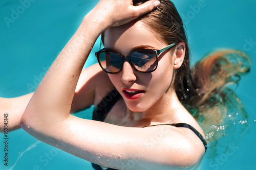 Portrait of young sexy lady swimming in the pool
