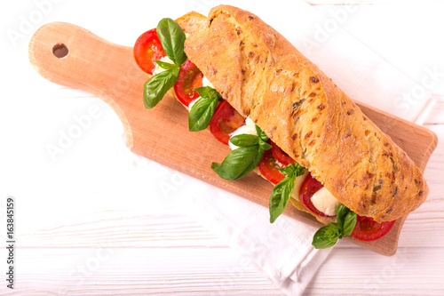 Ciabatta sandwich with caprese salad, basil, tomatoes, mozzarella photo