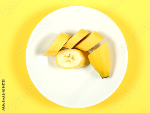 банан фрукт лежит на белой тарелке на жёлтом фоне