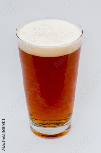 Amber Ale beer with foam in glass on a white background.