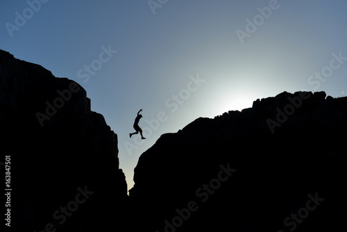 man who jumped on the rocks in silhouette