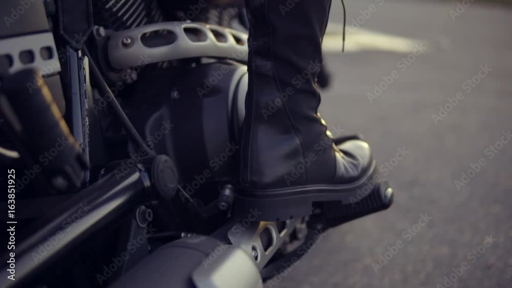 Close up shot of a leg in black boots of anonymous biker girl shifting gears Close up shot of a leg in black boots of anonymous biker girl shifting gears