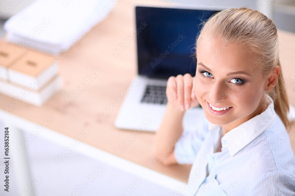 Attractive businesswoman sitting on a desk with laptop in the office