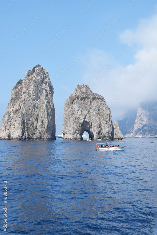 two of the Faraglioni rocks with boat approaching, Capri, Italy