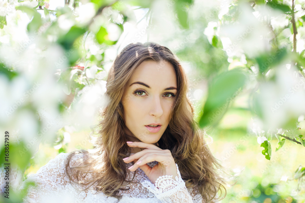 Beautiful brunette posing in blossoming apple-trees