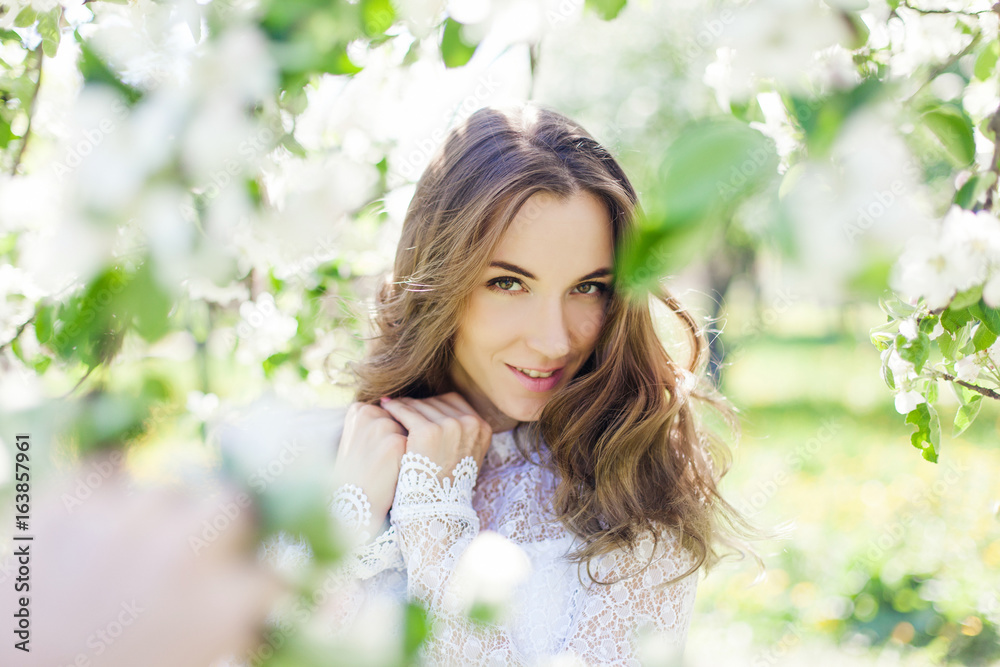 Fototapeta premium Beautiful brunette posing in blossoming apple-trees