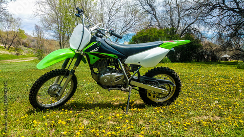 Kids 125cc Kawasaki Dirt Bike sitting in a field of grass and flowers in Wyoming on Summer Day photo