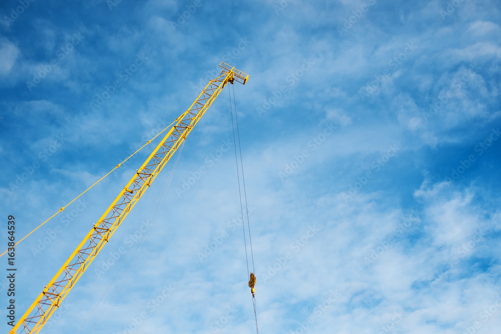 Part of yellow construction crane, on blue sky background Part of yellow construction crane, on blue sky background