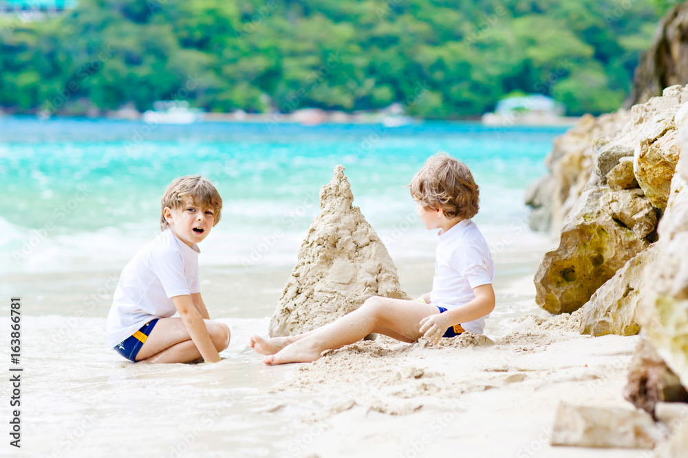 Two kid boys building sand castle on tropical beach Two kid boys building sand castle on tropical beach