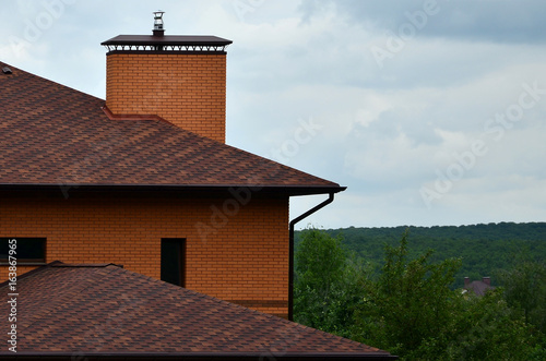 The house is equipped with high-quality roofing of shingles (bitumen tiles). A good example of perfect roofing. The roof is reliably protected from adverse weather conditions photo