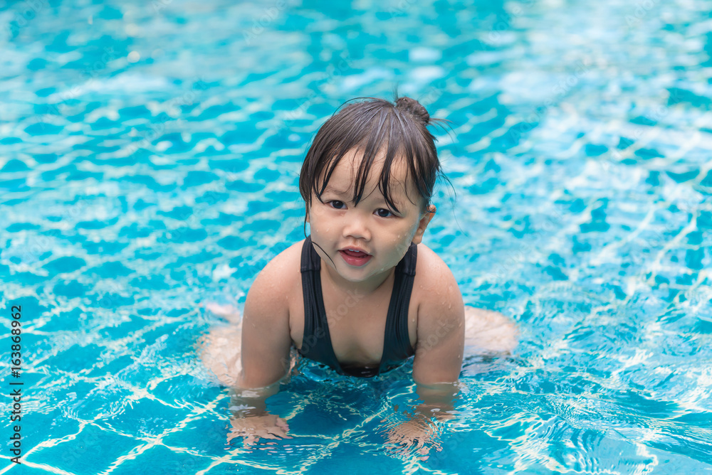 Cute girl or little child playing in swimming pool happily