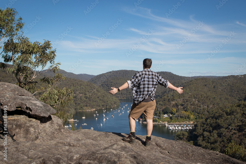 Fototapeta premium Man overlooking valley with arms wide