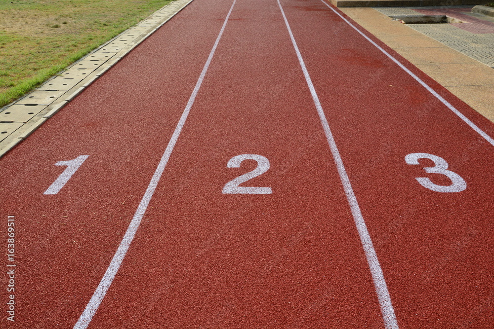 Fototapeta premium Red treadmill, track running at the stadium with green grass